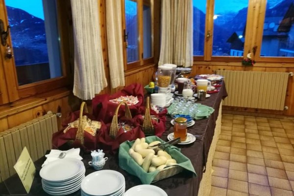 Bufetowy stół z jedzeniem i napojami przy oknie z widokiem na góry.