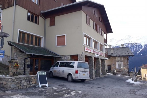 Budynek restauracji w górskiej okolicy z białym vanem zaparkowanym przed wejściem.