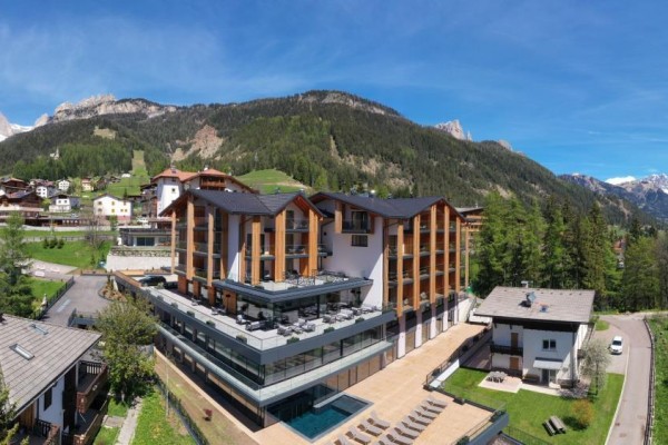 Nowoczesny hotel w górskim otoczeniu z ośnieżonymi szczytami w tle.