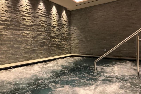 Wewnętrzne jacuzzi z kamienną ścianą i schodami.