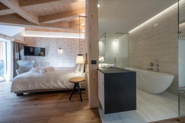 Nowoczesny pokój hotelowy z łóżkiem i otwartą łazienką z wanną.