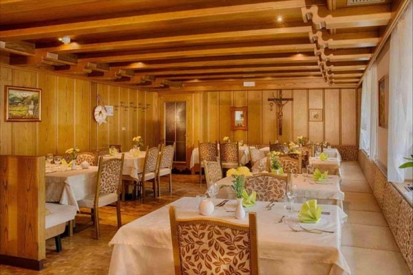 Wnętrze tradycyjnej restauracji z drewnianymi panelami i nakrytymi stołami.