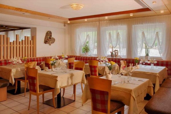 Elegancka restauracja z drewnianymi krzesłami i nakrytymi stołami przy oknie z kwiatami.