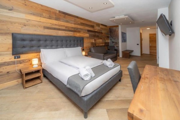 Nowoczesny pokój hotelowy z podwójnym łóżkiem i sofą.