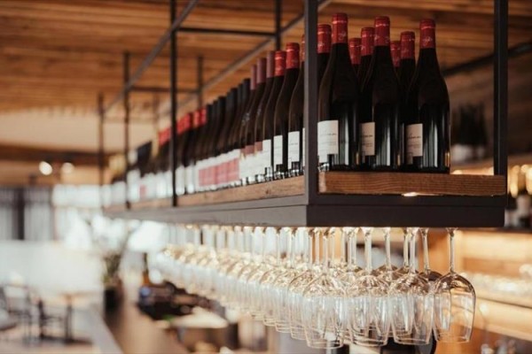 Rząd butelek wina i kieliszków zawieszonych pod sufitem w restauracji.