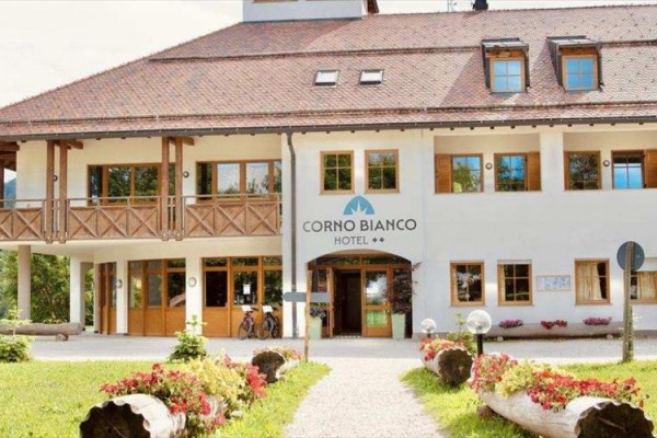 Hotel Corno Bianco z drewnianymi elementami i kwiatami przed wejściem.