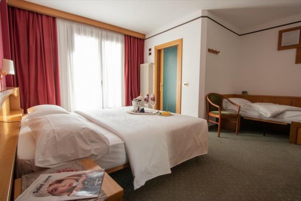 Pokój hotelowy z dwoma łóżkami, pościelą i magazynami na stole.