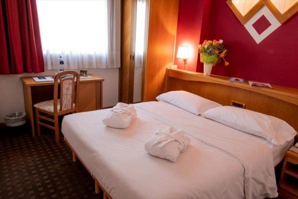 Pokój hotelowy z podwójnym łóżkiem, kwiatami i biurkiem.