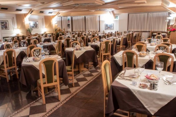 Przestronna restauracja z przygotowanymi stolikami i brązowymi obrusami.  