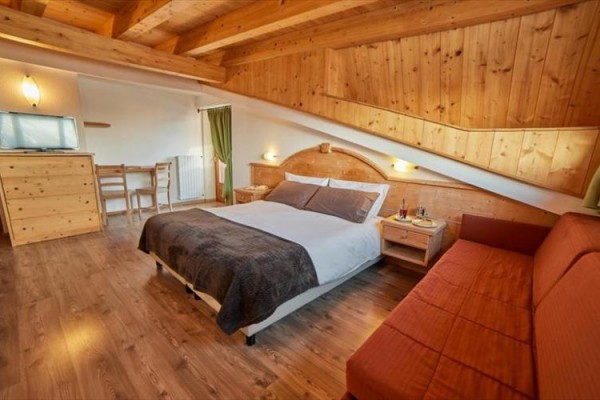 Pokój hotelowy z podwójnym łóżkiem, drewnianym wnętrzem i sofą.