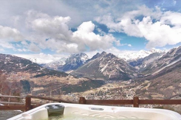 Zewnętrzne jacuzzi z widokiem na ośnieżone góry i dolinę.