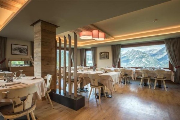 Restauracja z drewnianymi meblami i widokiem na góry.