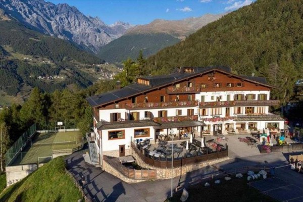 Hotel górski otoczony lasami i górami z kortem tenisowym obok.