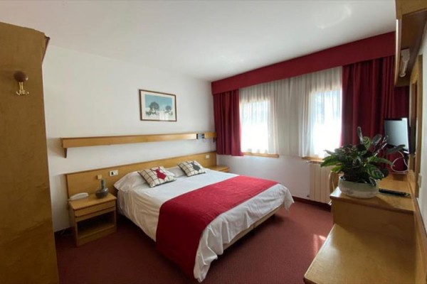 Pokój hotelowy z łóżkiem małżeńskim, czerwonymi akcentami i obrazem na ścianie.