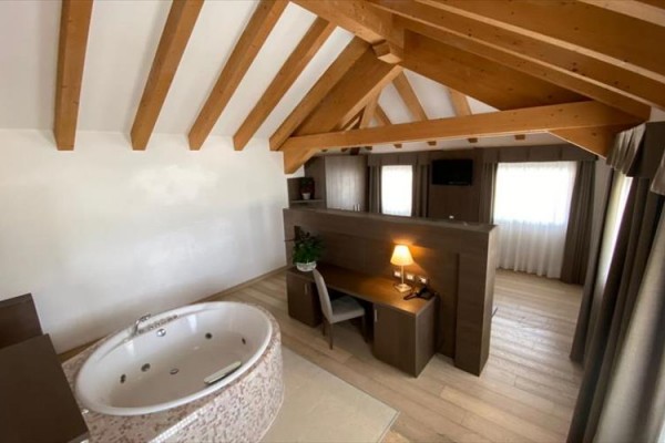 Pokój na poddaszu z jacuzzi i drewnianym sufitem.