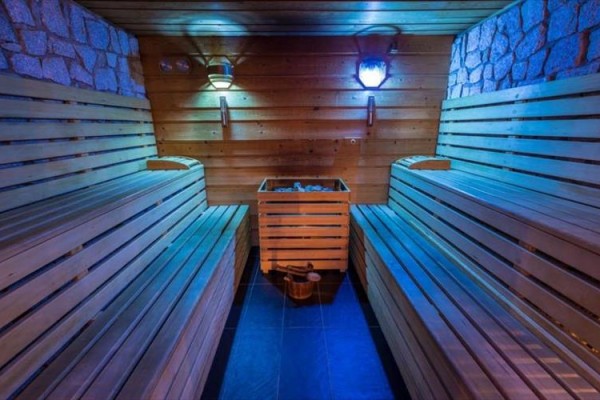 Drewniana sauna z oświetleniem i ławkami po obu stronach.