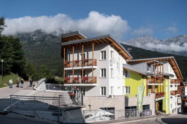 Nowoczesny hotel w górskim krajobrazie z niebieskim niebem i chmurami.