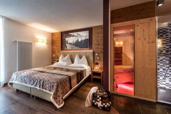 Luksusowy pokój hotelowy z łóżkiem małżeńskim, drewnianą boazerią i sauną.
