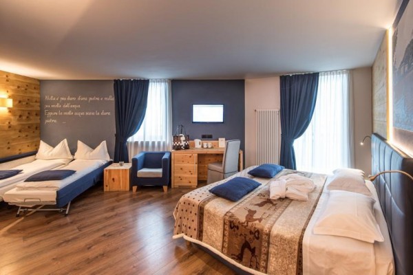 Nowoczesny pokój hotelowy z jednym łóżkiem małżeńskim i dwoma rozkładanymi łóżkami.
