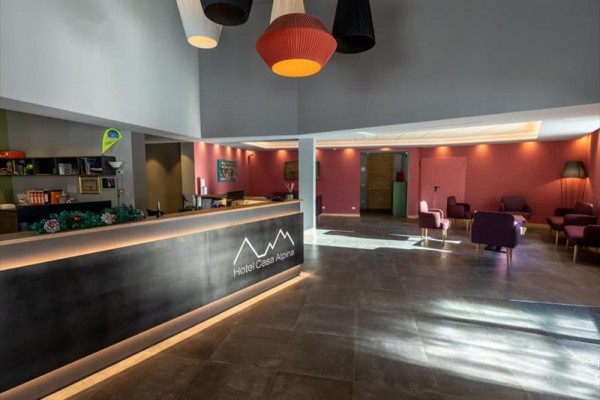 Recepcja hotelowa z nowoczesnym oświetleniem i zestawami wypoczynkowymi.