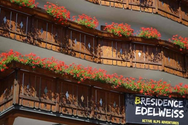 Balkony z drewnianymi balustradami ozdobione kwiatami oraz napisem 