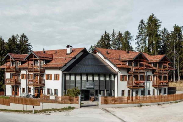Hotel z drewnianymi balkonami otoczony lasem.