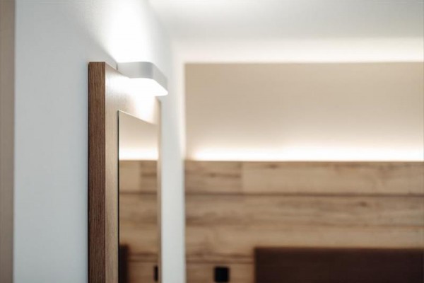 Drewniana rama lustra i nowoczesna lampa ścienna we wnętrzu pokoju.