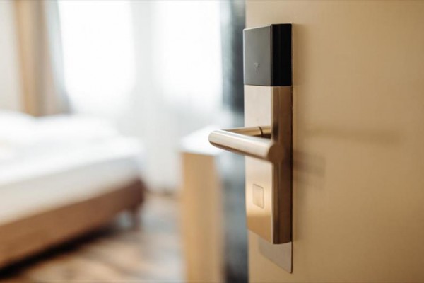 Drzwi z elektroniczną klamką prowadzące do jasnego pokoju.