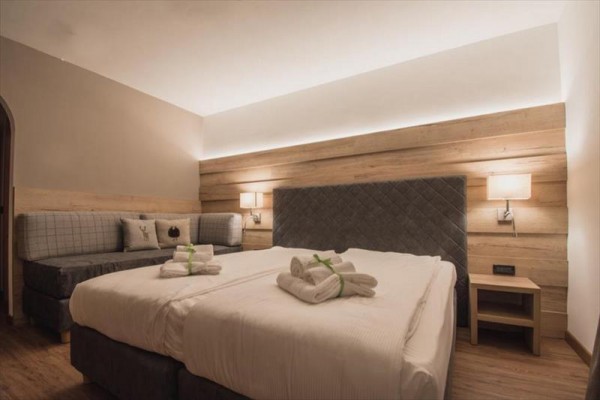 Nowoczesny pokój hotelowy z podwójnym łóżkiem i sofą, ozdobiony drewnianymi elementami.