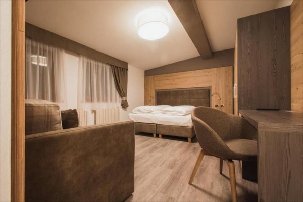 Nowocześnie urządzony pokój hotelowy z łóżkiem, biurkiem i krzesłem w drewnianym stylu.