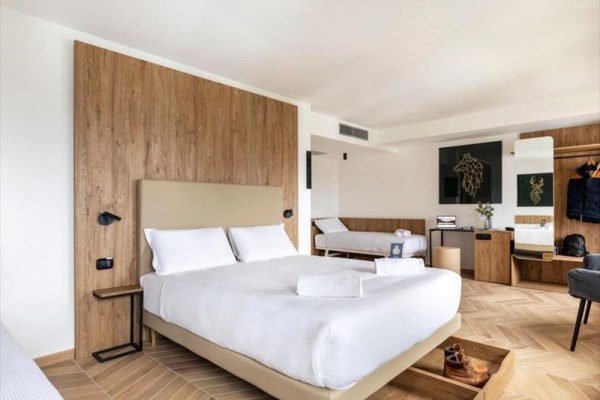 Nowoczesny pokój hotelowy z dużym łóżkiem, drewnianą okładziną i dekoracjami na ścianach.