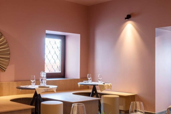 Nowoczesne wnętrze restauracji z różowymi ścianami i minimalistycznymi meblami.