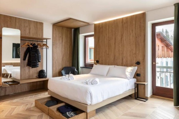 Nowoczesny pokój z łóżkiem małżeńskim, lustrem i otwartą szafą na ubrania.