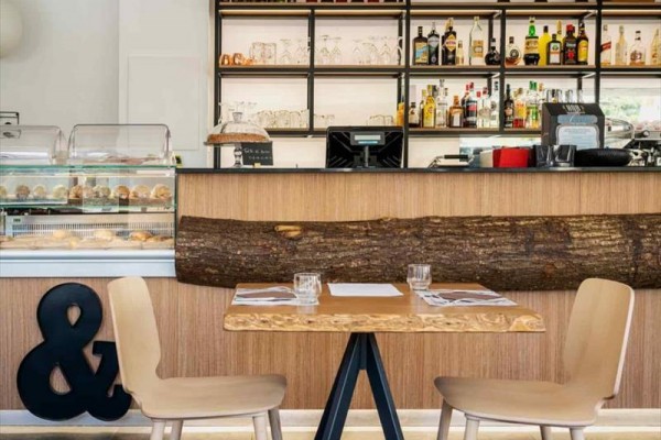 Wnętrze kawiarni z drewnianym blatem, krzesłami i stołami.