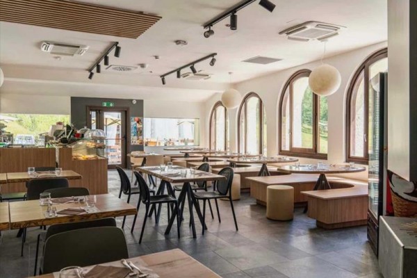 Nowoczesna restauracja z dużymi oknami i drewnianymi meblami.