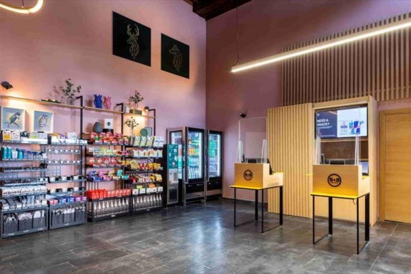 Sklep z regałami pełnymi jedzenia i napojów oraz dwoma ladami z kasami.