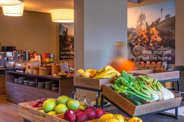 Hotelowa sala śniadaniowa z owocami i pieczywem na stołach.