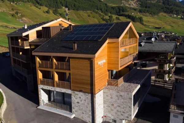 Nowoczesny drewniany budynek z panelami fotowoltaicznymi na dachu w górskim obszarze.