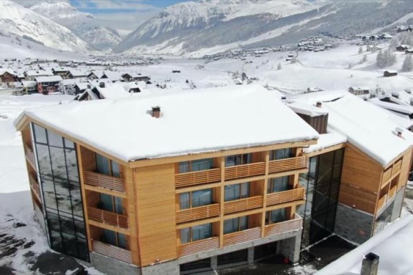 Nowoczesny drewniany budynek pokryty śniegiem w górskiej wiosce.