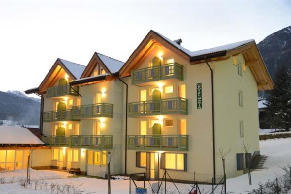 Hotel w kształcie T z balkonem i zaśnieżonym krajobrazem w tle.