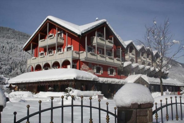 Czerwony górski hotel otoczony śniegiem z górami w tle.