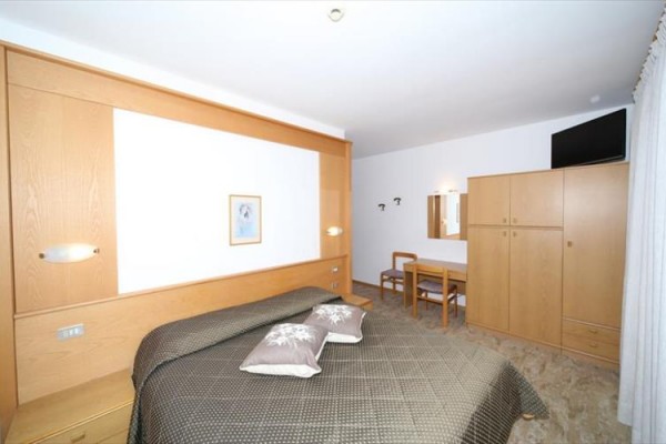 Pokój hotelowy z dużym łóżkiem, drewnianymi meblami i telewizorem.