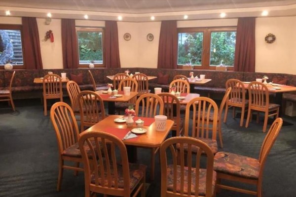 Restauracja z drewnianymi krzesłami i nakrytymi stołami.