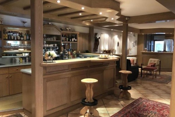 Przytulny bar z drewnianym wyposażeniem i dużą ilością napojów na półkach.