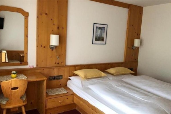 Pokój hotelowy z drewnianymi meblami, łóżkiem małżeńskim i biurkiem z lustrem.  