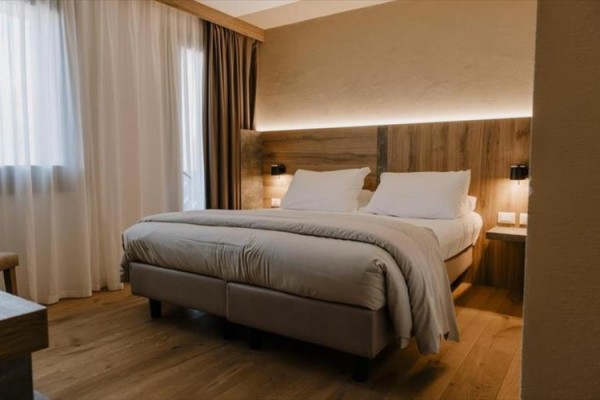 Nowoczesny pokój hotelowy z podwójnym łóżkiem i drewnianymi meblami.
