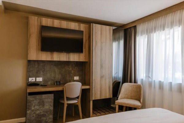 Nowoczesny pokój hotelowy z biurkiem, telewizorem i dwoma krzesłami.