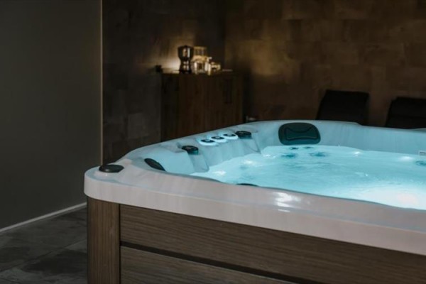 Jacuzzi w delikatnie oświetlonym pomieszczeniu z dekoracyjnymi świecami.