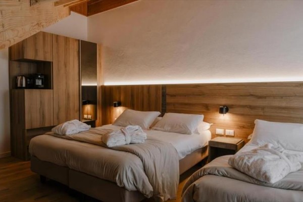 Nowoczesny pokój hotelowy z dwoma łóżkami małżeńskimi i drewnianymi meblami.  