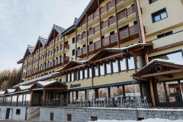 Budynek hotelu z ośnieżonym dachem i drewnianymi balkonami.
